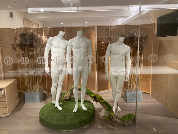 Three mannequins styled in David Donahue menswear on a moss-covered display base